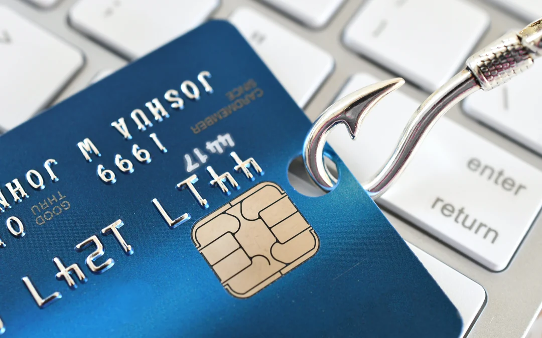 Blue bank card on a keyboard with a fishing hook, representing phishing fraud