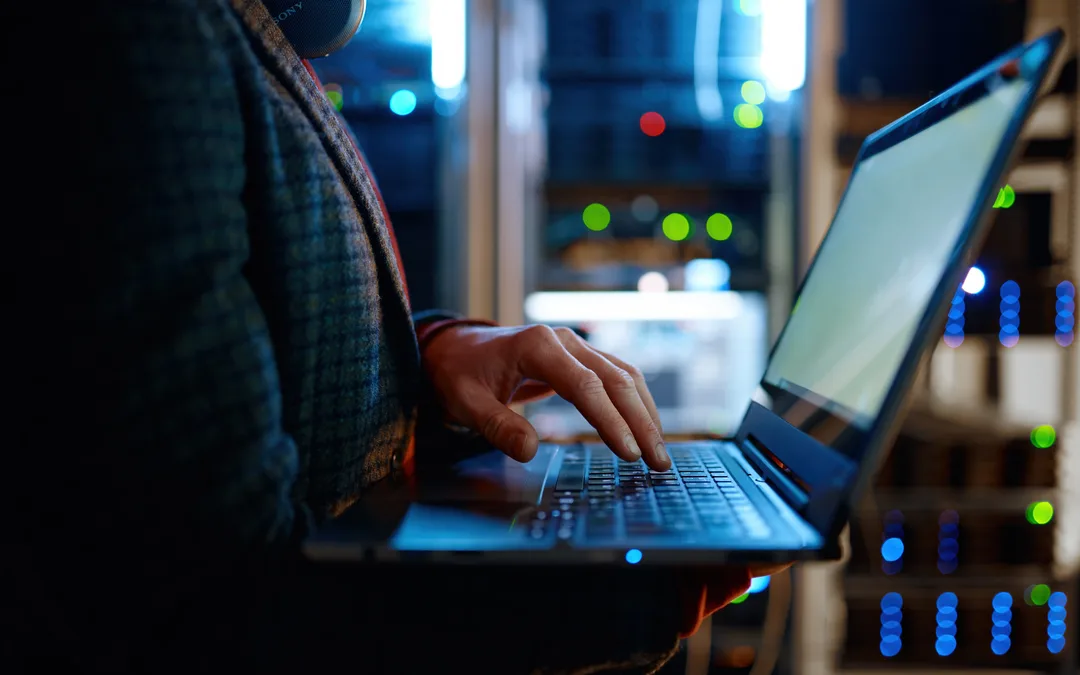 Technician using a laptop beside server equipment in a data centre